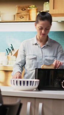 Dikey Videocu Kadın kahvaltı masasında portakal suyunu bardaklara dolduruyor, yumurtaların yanında meyve ve hamur işi ile zengin bir ev yemeği servis ediyor. Genç kız ve koca için şirin bir sabah rutini.