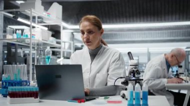 Gergin nanoteknoloji araştırmacıları laboratuarda kafa basıncı hissediyorlar, dizüstü bilgisayar yazılımı kullanıyorlar, sürücü tedavisi keşfi yapıyorlar. Migreni olan laboratuar teknisyeni laboratuvarda biyoenformatik uygulama kullanıyor. Kamera A.