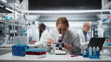 Patoloji slaytlarını inceleyen tarih teknisyeni araştırma merkezinde mikroskop altında. Tıbbi yenilikleri araştıran kadın araştırmacı kendini adamış hücresel analiz çalışmaları, kamera A