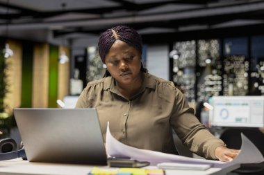 Çalışma saatleri dışında karanlık bir ofiste çalışan ofis çalışanları, veri güncellemeleri ve iş girişimleri için rapor numaralarını araştırıp belgelemeye odaklanıyor. Finans hedefleri ve proje geliştirme.