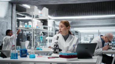 Ekip araştırmacıları klinik deneyler sırasında cam şişelerdeki sıvıları incelerler. Araştırma tesisi çalışma arkadaşları cam kaplarda kimyasalları karşılaştırıyor, test formülü, kamera A