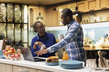 Mutlu çift birlikte lezzetli bir kahvaltı hazırlıyor ve internetteki bir yemek tarifini takip ederek kahve içiyor. Tost dilimleri, ev yapımı hamur işleri ve mutfakta sağlıklı yiyecekler yemeye hazırlanıyorum..