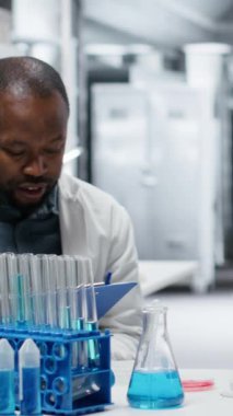 Meslektaşım panoya teşhis bulgularını yazarken dikey video patolojisti biyopsi slaytını inceliyor. Tıbbi uzmanlar klinik laboratuarında petri kabı hastalıklarını belirlemek için birlikte çalışıyorlar.