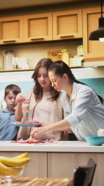 Pizza günü ebeveynler ve çocuklarla mutfakta dikey video aile zamanı mozzarella ve pepperoni gibi malzemeler ekleniyor. Eğlenceli ve lezzetli ev yemekleri, kahkahalarla çevrili. Kamera A.