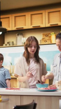 Dikey video ebeveynleri çocuklarına lezzetli ev yapımı pizza yapmayı öğretiyor, ergenlik öncesi kız ve çocuk da dahil oluyor ve birlikte yemek yapmayı öğreniyorlar. Hafta sonu aktiviteleri sırasında aile zamanı. Kamera.