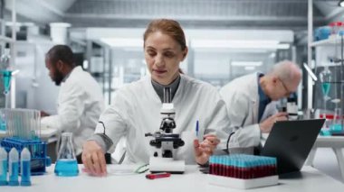 Laboratuvardaki tarih teknisyeni yapısal bozukluklar ya da safsızlıklar için ince cam kaydırağını inceliyor. Laboratuardaki kadın, mikroskop kullanarak görsel kalite kontrolü yapıyor. Kamera B