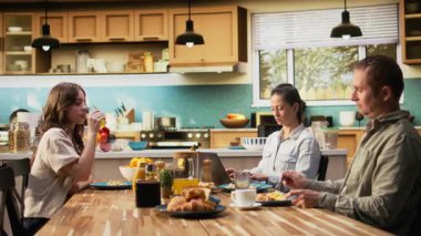 Annem dizüstü bilgisayarla uzaktan kontrol ederken, ergen kız, babası, ailesi ve kızıyla mutfakta ev yapımı yemek yerken sohbet ediyor. Hafta sonları bağ kurma zamanı. Kamera A.