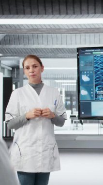 Dikey video tıp fakültesi profesörü moleküler biyoloji kavramları hakkında araştırmacılara danışmanlık yapıyor. Laboratuardaki kadın DNA organizma yapısını öğrencilere açıklamak için ekranı kullanıyor, kamera A