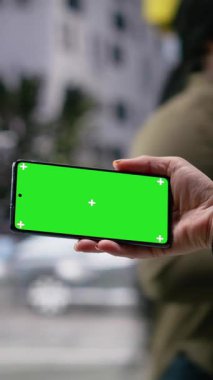 Metropolitan yaya geçidi boyunca ilerleyen ve dinamik kentselliği ve modern şehir kültürünün günlük hareketlerini gösteren çok kültürlü kalabalık yakınlarındaki akıllı telefondaki dikey video maketi. Kamera B.