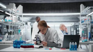 Hücresel analiz için bilimsel mikroskop kullanan gülümseyen tıbbi laboratuvar teknisyeninin portresi. Optik cihaz teçhizatı ve kamera A ile laboratuvarda örnek inceleme yapan mutlu orta yaşlı kadın.