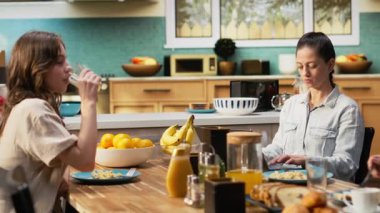 Annem dizüstü bilgisayarla uzaktan kontrol ederken, ergen kız, babası, ailesi ve kızıyla mutfakta ev yapımı yemek yerken sohbet ediyor. Hafta sonları bağ kurma zamanı. Kamera B.