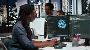 Ofisteki yazılım geliştiricisi not defterine yazarak yapay zeka sistemindeki hataları düzeltmeye çalışıyor. Bilgi işlem uzmanı masadan not alıyor, teknik başlangıçta sinirsel ağ hataları çekiyor, kamera B