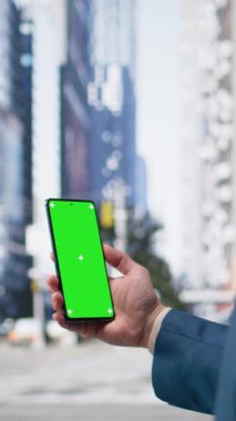 Yaya geçidinde trafiğin yanından geçen Asyalı bir adam tarafından tutulan dikey video krom anahtar ekranı, şehir kültürünün ritmi ve çeşitli yetişkinler aktif bir metropol caddesinde geziniyor. Kamera A