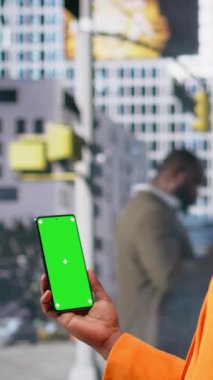 Dikey Video Dikey Ekranı, iş bölgesinde yürüyen yayalar grubunun yanında siyahi bir kadının telefonuyla izole edilmiş. Şehir hareketi, aktif yaşam tarzı ve gerçekçi sokak hayatı