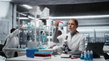 Hematoloji uzmanı. Kırmızı kan hücresi anormallikleri için kan örneklerini analiz ediyor. Sanguine sıvısı şişeleri üzerinde araştırma yapan teknisyen anemi tiplerini, kamera A 'yı teşhis ediyor.