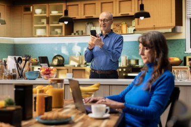 Sakin yaşlı bir adamın portresi mutfak vitrininde yemek ve kahveyle rahat bir an sergiliyor. Huzurlu bir emeklilik yaşamını doğal bir rutin ile kucaklıyor, refah içinde..