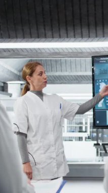 Dikey video tıp fakültesi profesörü öğrenciler için ileri hücre biyolojisi semineri düzenliyor. Akademik uzman laboratuvarda dijital ekran ve kamera kullanarak mikroskobik hücre bölünme işlemlerini açıklıyor