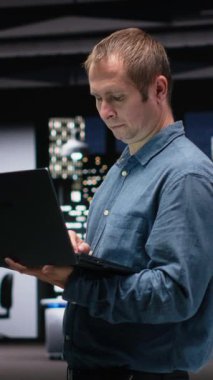 Dikey video yazılım geliştiricisi dizüstü bilgisayar kullanarak yapay zeka sistemindeki hataları düzeltmeye çalışıyor. Teknoloji uzmanları, teknolojik başlangıç işyerindeki sinirsel ağ hatalarını dizüstü bilgisayarla görüntüler.