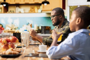 Ebeveynler kahvaltıda aileleriyle gazete makalelerini okurlar, omlet ve hamur işlerini birlikte yerler. Baba evde çocuklar ve eşle sabah rutininin keyfini çıkarıyor..