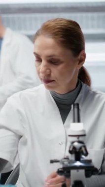 Dikey video hematoloji uzmanı. Kırmızı kan hücresi anormallikleri için kan örneklerini analiz ediyor. Sanguine sıvısı şişeleri üzerinde araştırma yapan teknisyen anemi tipleri, kamera B