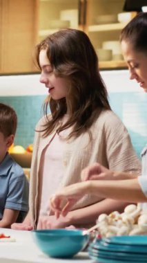 Dikey Videolu neşeli ebeveynler çocuklarına sebzeleri güvenli bir şekilde pişirmeyi ve kesmeyi öğretiyor, aileler eski tariflerden ev yapımı pizza yapmaktan hoşlanıyor. Annem ve babam verimli yemek pişirme adımlarını anlatıyor. Kamera B.