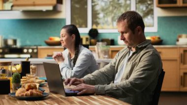 Yorgun bir çalışan baba kahvaltıda dizüstü bilgisayarda yazı yazıyor, bilgisayarını kapatıyor ve ailesiyle aşırı derecede stresli ve fazla çalışıyor. Evde canı sıkkın bir baba var. Kamera B.