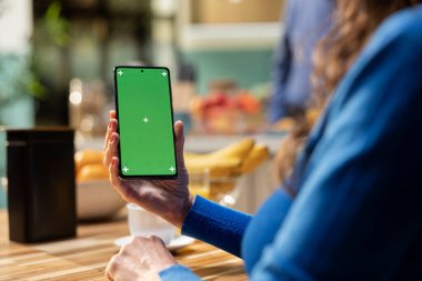 Cep telefonundaki yeşil ekranda yaşlı insanlar sakin bir sabah rutininin keyfini çıkarırken mutfak masasında kahve ve hamur işi servis ediyorlar. İzole edilmiş ve rahatlatıcı ekranı olan bir aygıta bakıyorsun.