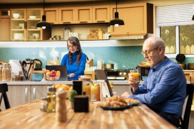 Huzurlu bir gülümsemeyle ev mutfağında duran yaşlı emekliler emekliliğin tadını çıkarıyorlar. Portre huzurlu refahı, sağlıklı yemek anlarını ve pozitif yaşam tarzını yansıtır..