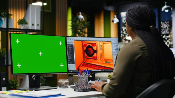 Ofiste birden fazla monitör kullanarak oyun geliştirme üzerinde çalışan Afrikalı Amerikalı kadının yanındaki yeşil ekran. Kadın mühendis yazılımda fütüristik bir uzay gemisi istasyonu yaratıyor. Kamera B.