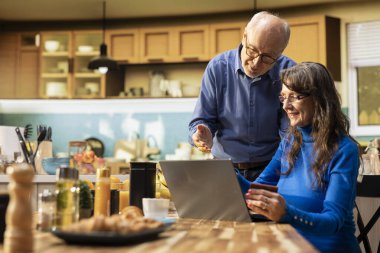 Emekli insanlar internetten kredi kartıyla yiyecek alışverişi yapıyor, market alışverişlerini inceliyor ve laptop 'daki uygulama arabasında sağlıklı yiyecekler yiyorlar. Uygun ev teslimatı seçenekleri.