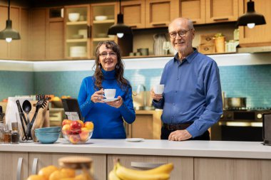 Apartman mutfağındaki yaşlı insanların portresi pozitif emeklilik hayatını yansıtan bir kahve fincanıyla sakin bir anın tadını çıkarıyor. Evde rahat ve neşeli bir yaşam tarzı gösteren yaşlı bir çift..