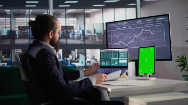 Tablet üzerindeki dikey yeşil ekranda erkek profesyonel analiz şirketi verileri, bilgi grafikleri ve verimlilik raporları iş yönetimi için karar vermeye yardımcı oluyor. KPI analizi.