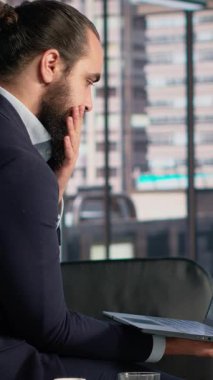 KPI 'leri ve ofisindeki dizüstü bilgisayardaki görüşleri inceleyen Dikey Video İşletme Lideri, şirket veri raporları nedeniyle mali yönetim ve karar verme ile meşgul. Profesyonel performansı analiz eder