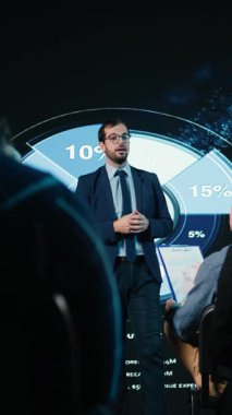 Seyircilerle iş görüşmesi için zemin hazırlayan dikey video konuşmacısı, konferans salonundaki panel tartışması ile profesyonel konferans zirvesi. Uluslararası alanda çalışan beyaz yakalı işçiler