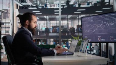 Tablet ve dizüstü bilgisayardaki şirket veri numaralarını inceleyen ve değerlendiren, iş geliştirme raporları ve KPI 'leri inceleyen bir erkek. İşyeri yönetimi ve yürütme yönetimi.