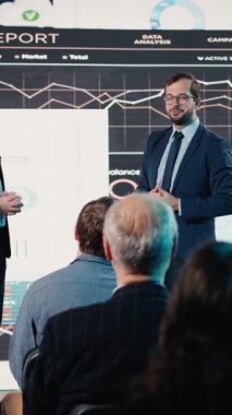 Dikey video iki profesyonel adam çeşitli grup izleyicileri için konferans konuşması yapıyor. Konferans salonundaki uluslararası iş etkinliğine profesyoneller, ağ oluşturma ve liderlik katılıyor