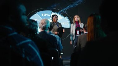 Çeşitli bayan sunucular uluslararası zirvede bir iş konferansına ev sahipliği yaparak liderlik taktiklerini tartışmak üzere sahneye çıktılar. Konferans salonunda ağ toplantısı. Kamera A.