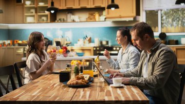Babasıyla mutfak masasında dizüstü bilgisayarda yazmakla meşguldü. Kahvaltıda küçük kızı ve karısını görmezden geliyordu. Kafası karışık baba kızıyla mesafeli..