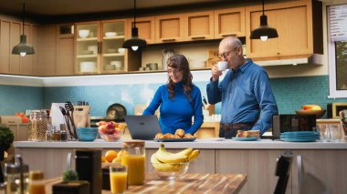 Yıllanmış karı koca evlerinin mutfağında dizüstü bilgisayar uygulamalarına göz atıyorlar, kahve ve huzur içinde dinlenmenin tadını çıkarıyorlar. Neşeli bir yaşam tarzı, mutlu bir yaşam ve emeklilikte rahat anlar. Kamera A.