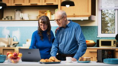 Yıllanmış karı koca evlerinin mutfağında dizüstü bilgisayar uygulamalarına göz atıyorlar, kahve ve huzur içinde dinlenmenin tadını çıkarıyorlar. Neşeli bir yaşam tarzı, mutlu bir yaşam ve emeklilikte rahat anlar. Kamera B.