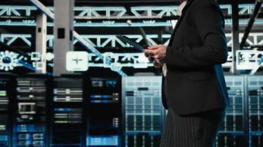 Veri merkezinde yürüyen teknisyen, AR simülasyonunu kullanarak bilişim altyapısında güvenlik denetimi yapıyor. Güvenlik duvarı korumasını doğrulamak için VFX bileşik görüntüleme kullanan sunucu odası uzmanı, kamera A