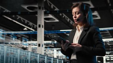 Teknoloji sorunları teşhis ediliyor, AR holografik bilişim destek çalışanı veri merkezinde. Kulaklık mikrofonuyla konuşmak, artırılmış gerçeklik simülasyonu ve kadın ağ sorunlarını belirlemek, kamera A