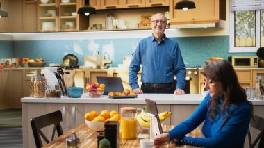 Apartman mutfağındaki neşeli yaşlı adamın portresi emeklilik süresince rahatlamış bir zevk gösteriyor. Yaşlı kişi tezgahın yanında duruyor, günlük ev bakımını ve olumlu ev refahını kucaklıyor. Kamera A.