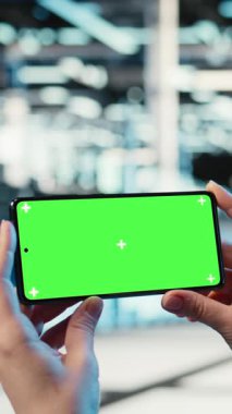 Sunucu merkezi çalışanının video izlerken kullandığı dikey video yeşil ekran model akıllı telefon. Veri merkezindeki yazılım geliştirici elinde kroma anahtar cep telefonu olan, online kliplere bakan, kamera A