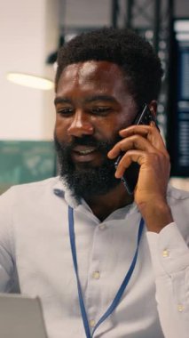 Dikey Video Siyah erkek profesyonel telefonda cep telefonuyla iletişim kuruyor. KPI için iş istihbaratını destekleyen dizüstü bilgisayardaki görsel veriler, grafikler ve grafikler, stratejik