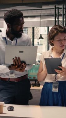 Dikey Video Portresi çok ırklı ekibi, ofiste birlikte çalışıyorlar, iş raporlarını gözden geçiriyorlar, görsel verileri inceliyorlar. Kurumsal işbirliği, öngörü ve planlama, örgütsel hedeflere ulaşmak