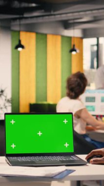 Tablet üzerindeki dikey video mavi ekran ve ofis çalışma alanındaki dizüstü bilgisayarda yeşil ekran, performans ölçümleri ve analizlerine odaklanan siyah iş adamı, görsel veri, KPI raporları ve iş zekası.