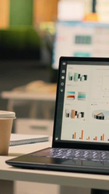 Boş iş ofisindeki laptop ekranında çalışan dikey video tahmin raporları, masa kurulumunda veri analizi ve performans ölçümleri gösteriliyor. Doğal ışık ile modern parlak çalışma ortamı.