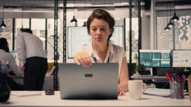 Bilgisayarını açıp masa başında günlük görevleri çözen, analitik üzerinde çalışan ve iş istihbaratını bildiren bir kadının portresi. Çok uluslu bir şirkette kadın profesyonel, verimlilik..