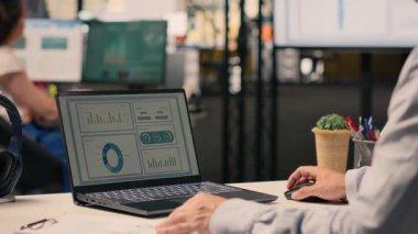 Masadaki dizüstü bilgisayardaki uyum verilerini inceleyen, performans değerlendirmesi yapan ve ofiste risk değerlendirmesi yapan profesyonel bir işçi. İş istihbaratı verimliliği için görsel veriler.